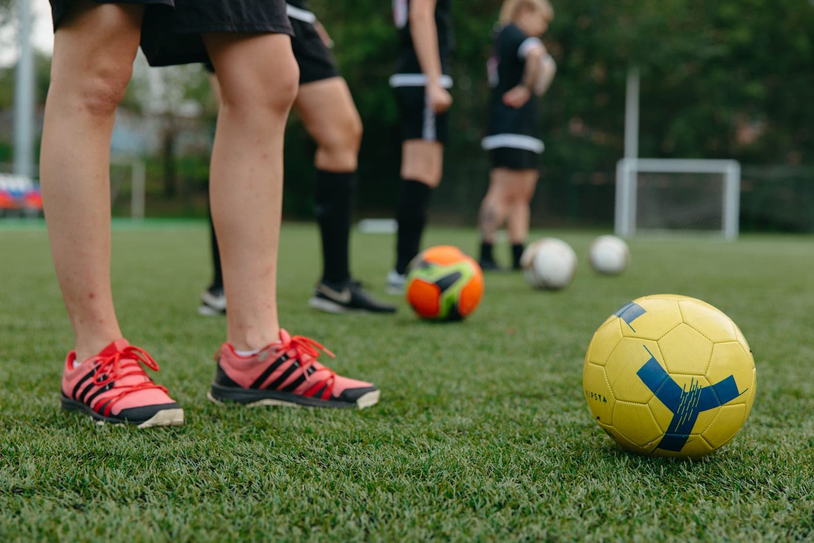 A young child's feet in soccer shoes next to a ball