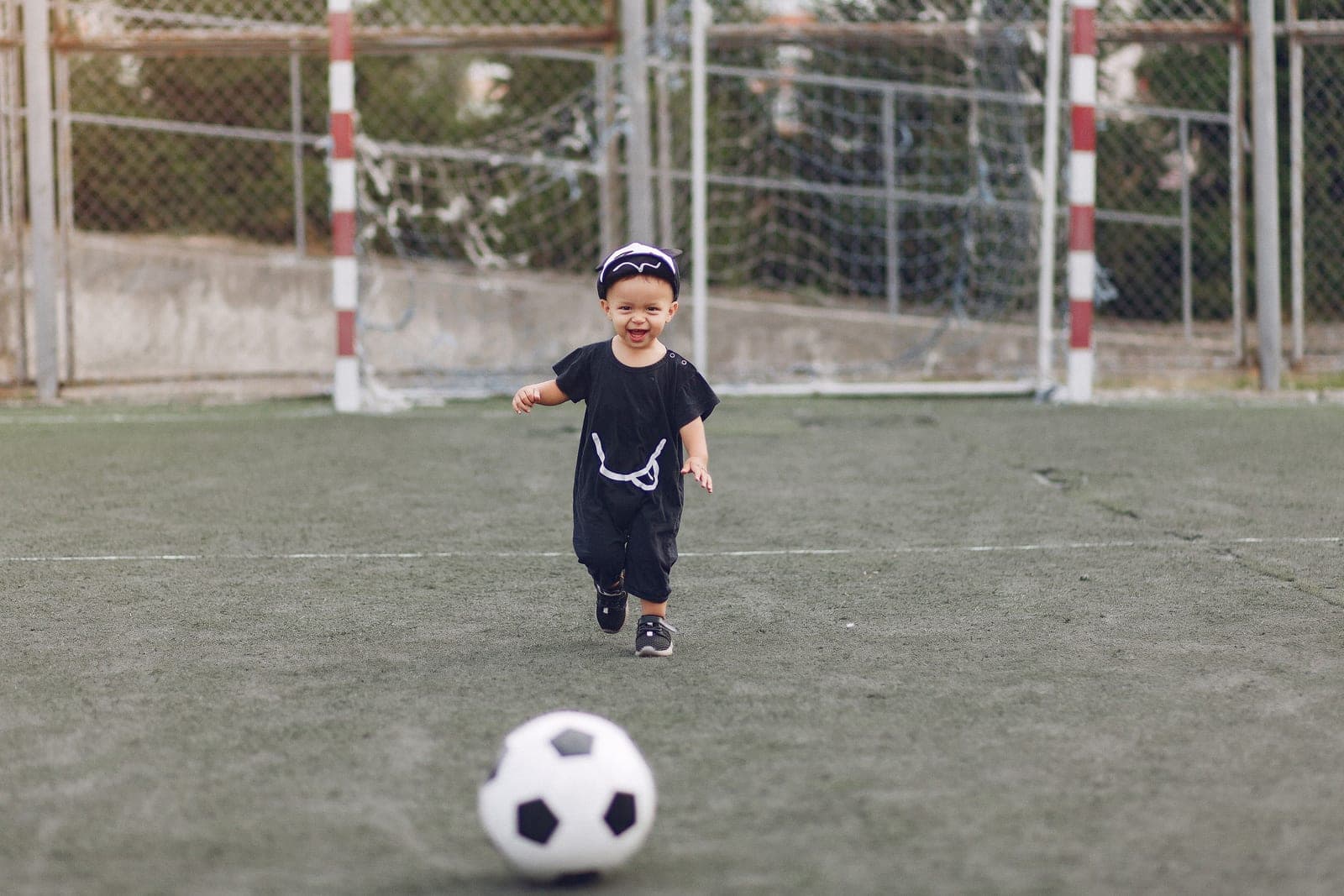 A toddler with a soccer ball on grass