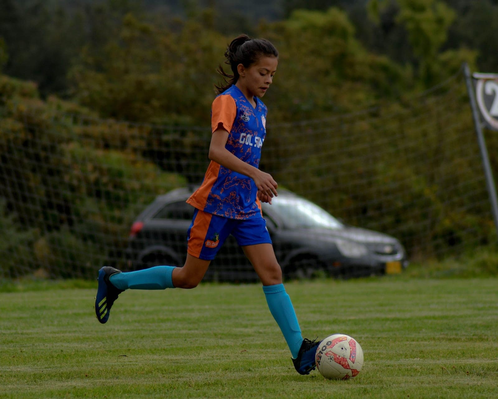 A young soccer player running with the ball